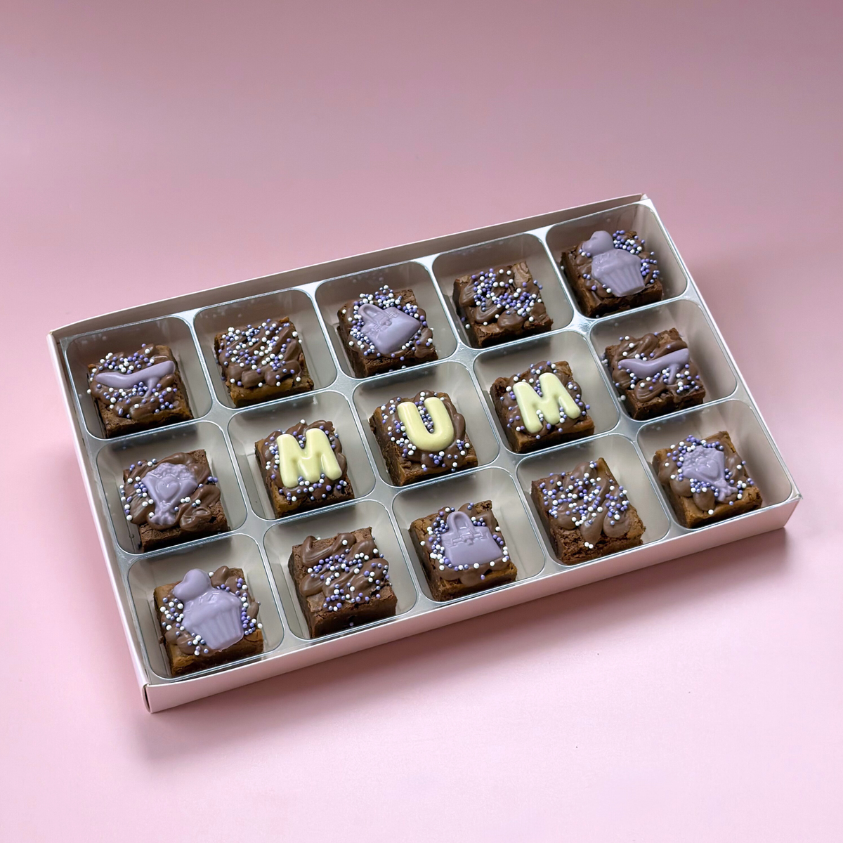 Box of 15 mini brownies with "Mum" in white chocolate letters between lilac handbag and shoe toppers