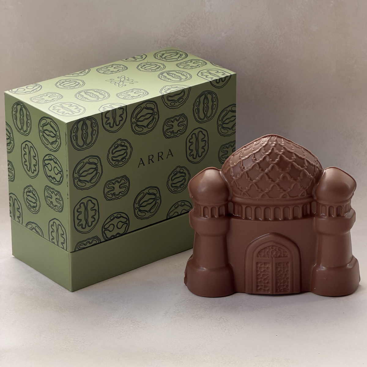 Milk chocolate mosque with a patterned dome and two minarets, next to its green Arra gift box