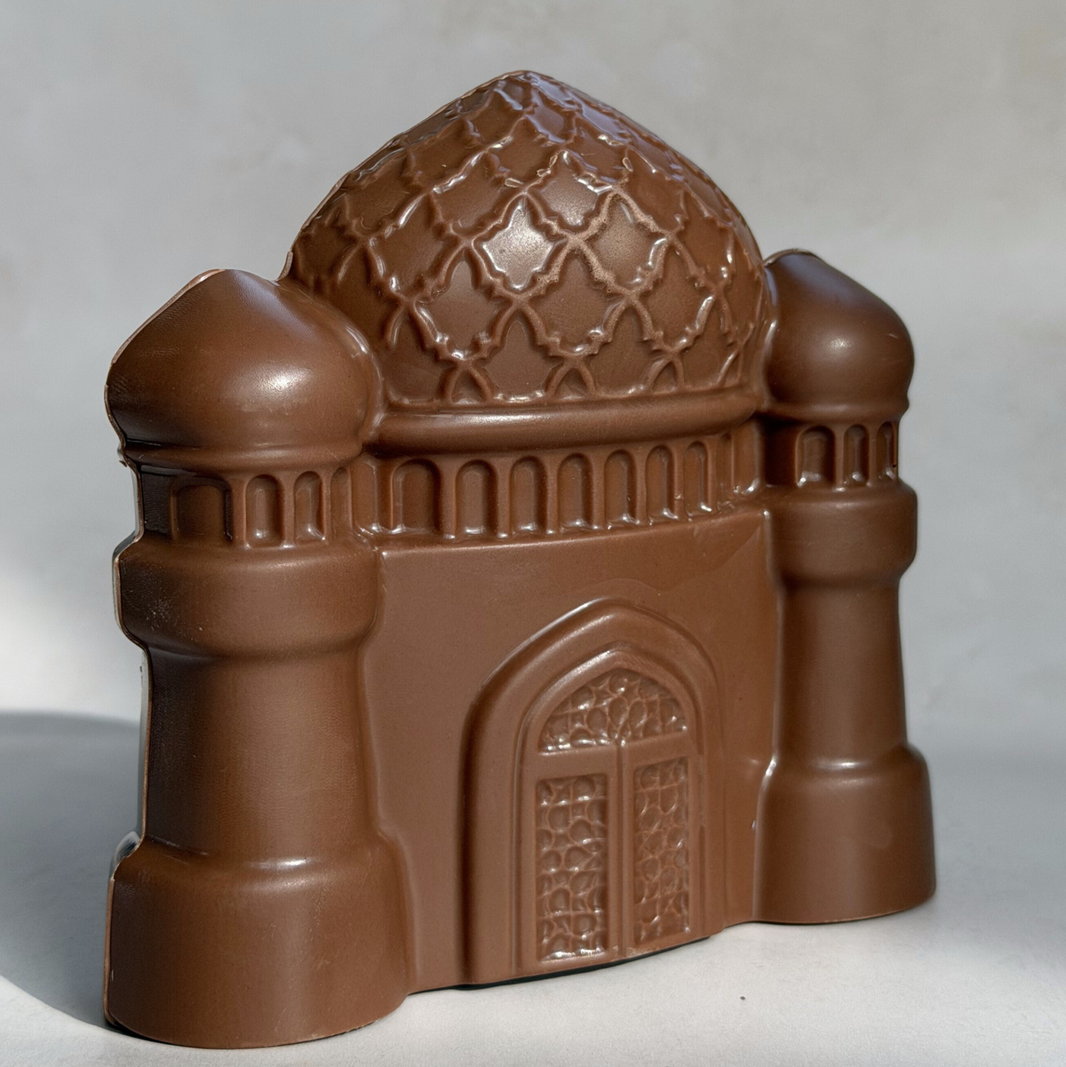 Close-up of a Belgian milk chocolate mosque with a patterned dome, two minarets and a carved door