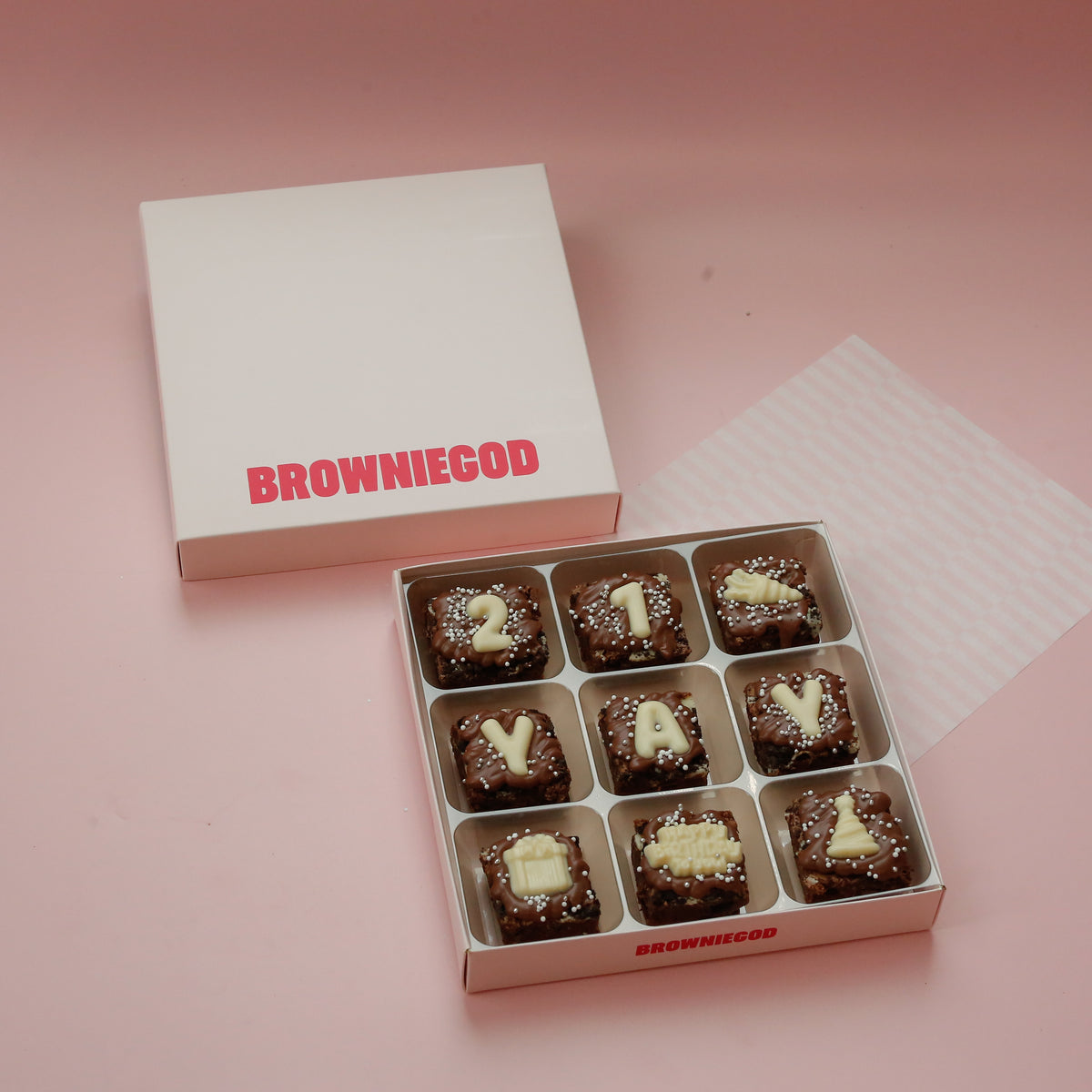 Box of 9 brownies spelling "21 yay" in white chocolate letters, with party hat and present icons