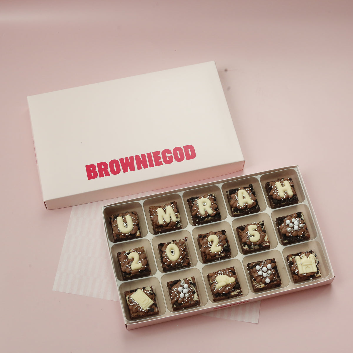 Box of 15 mini brownies spelling "Umrah 2025" in white chocolate letters, next to the Browniegod box lid