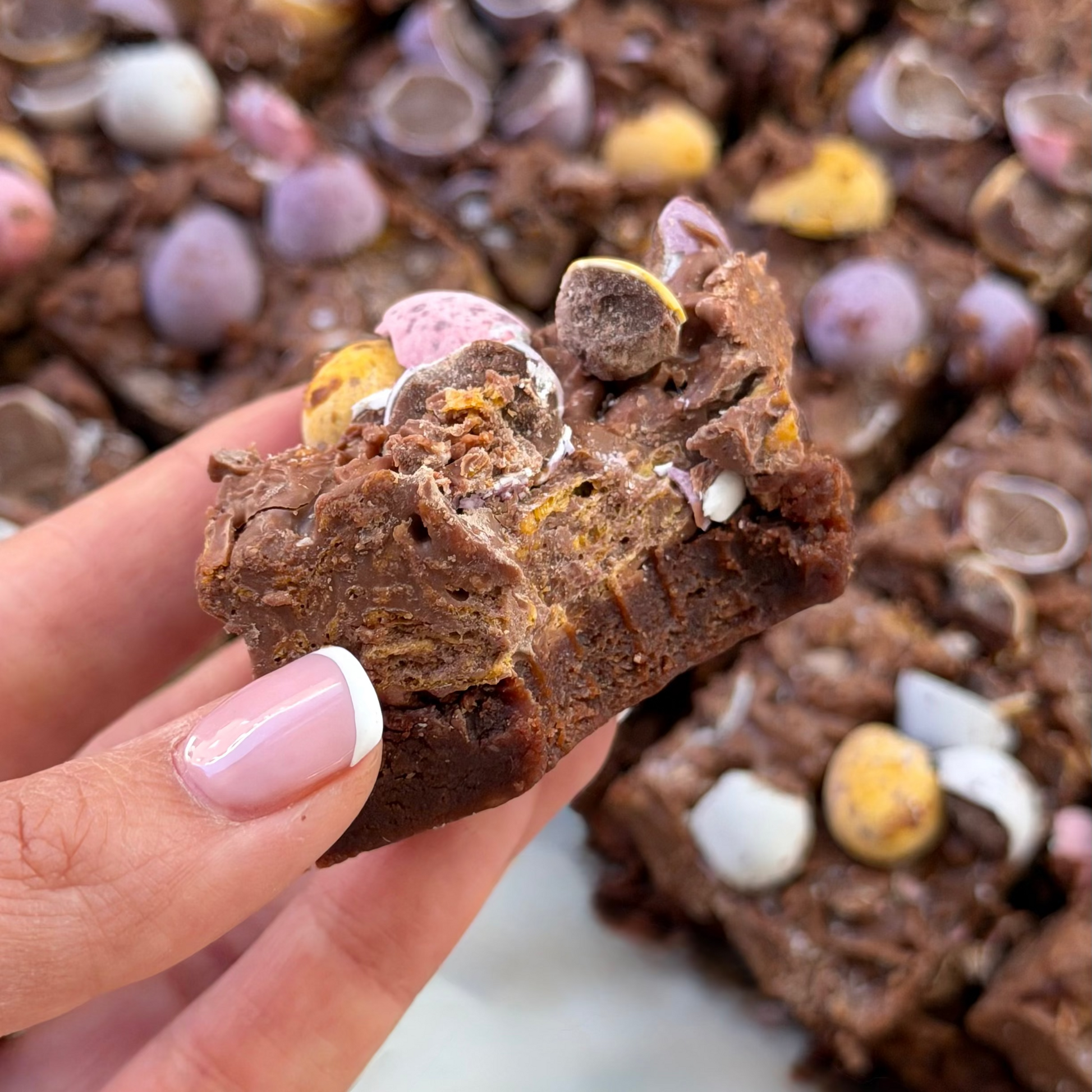 Chocolate brownie with mini eggs and cornflakes held by a hand