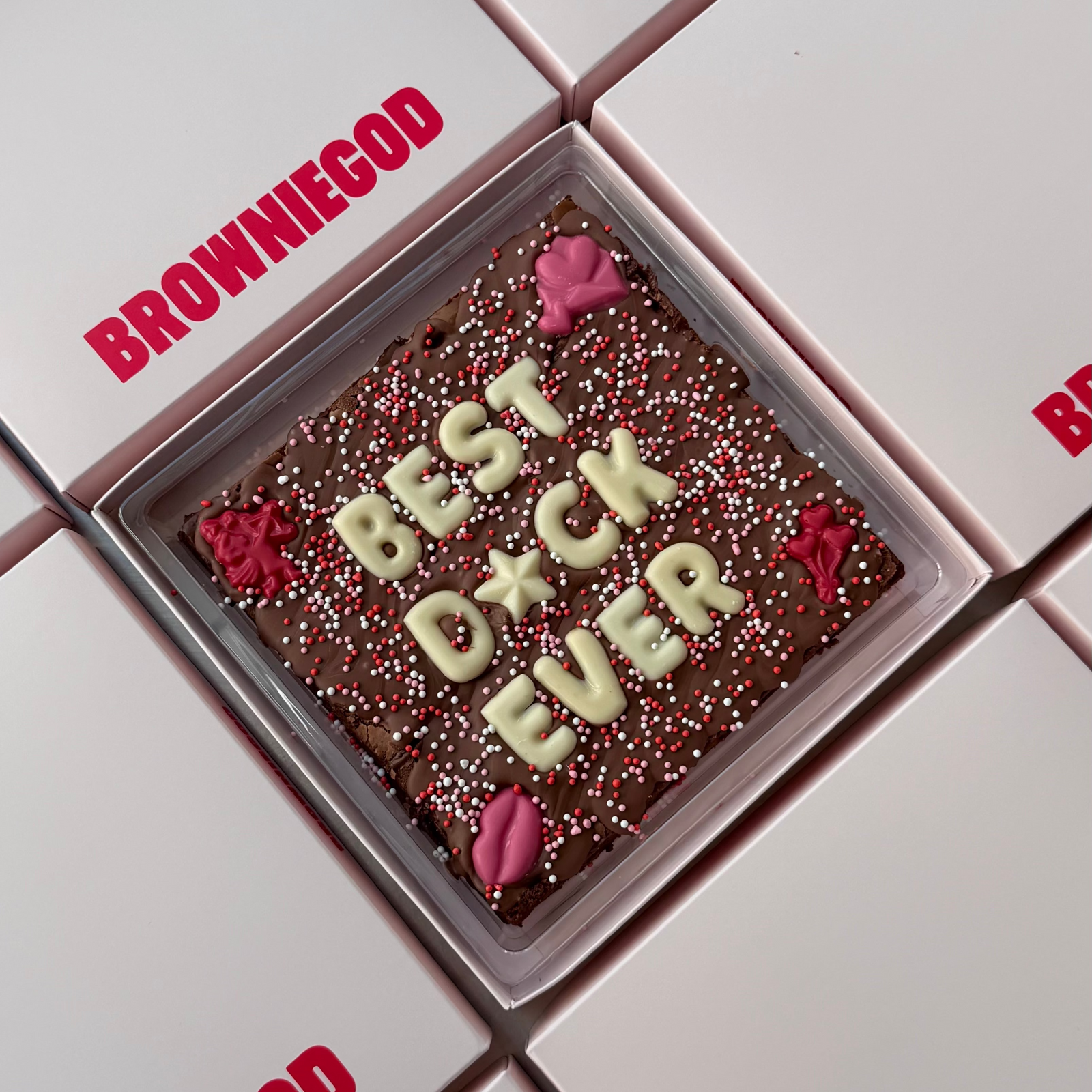 Valentine's brownie slab with a cheeky, censored message in white chocolate letters, red chocolate lips and pink sprinkles