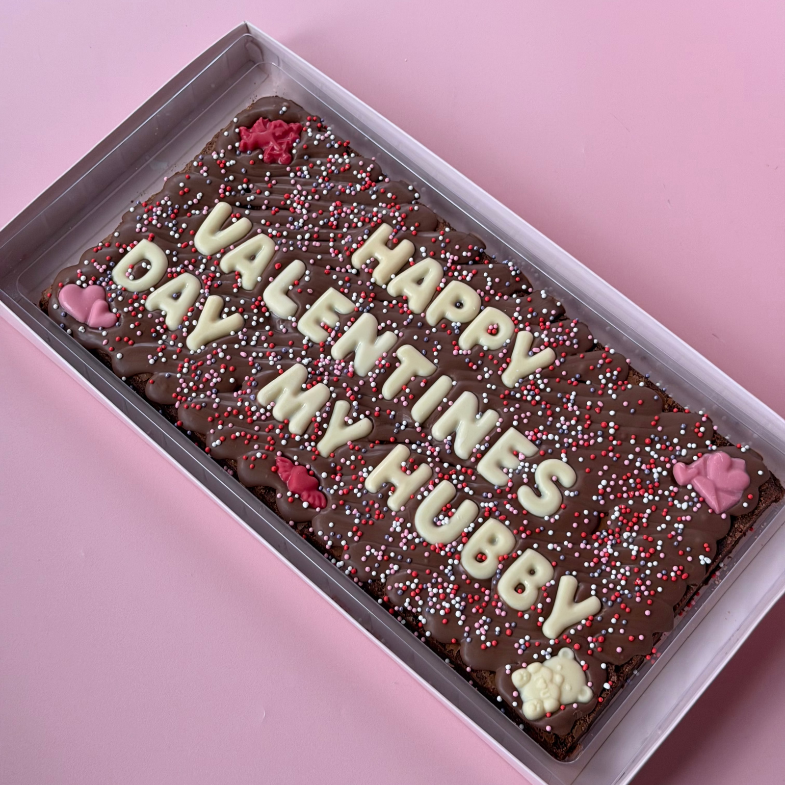 Long brownie slab reading "Happy Valentine's Day my hubby" in white chocolate letters with red and pink sprinkles
