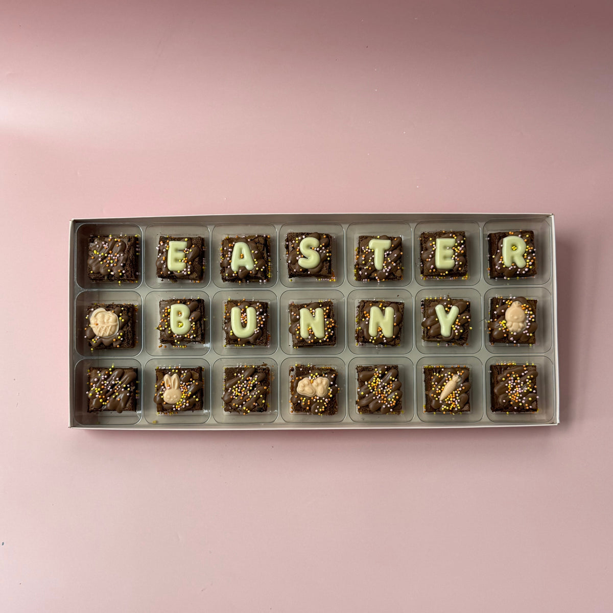 Box of 21 mini brownies spelling "Easter bunny" in white chocolate letters with bunny and egg toppers