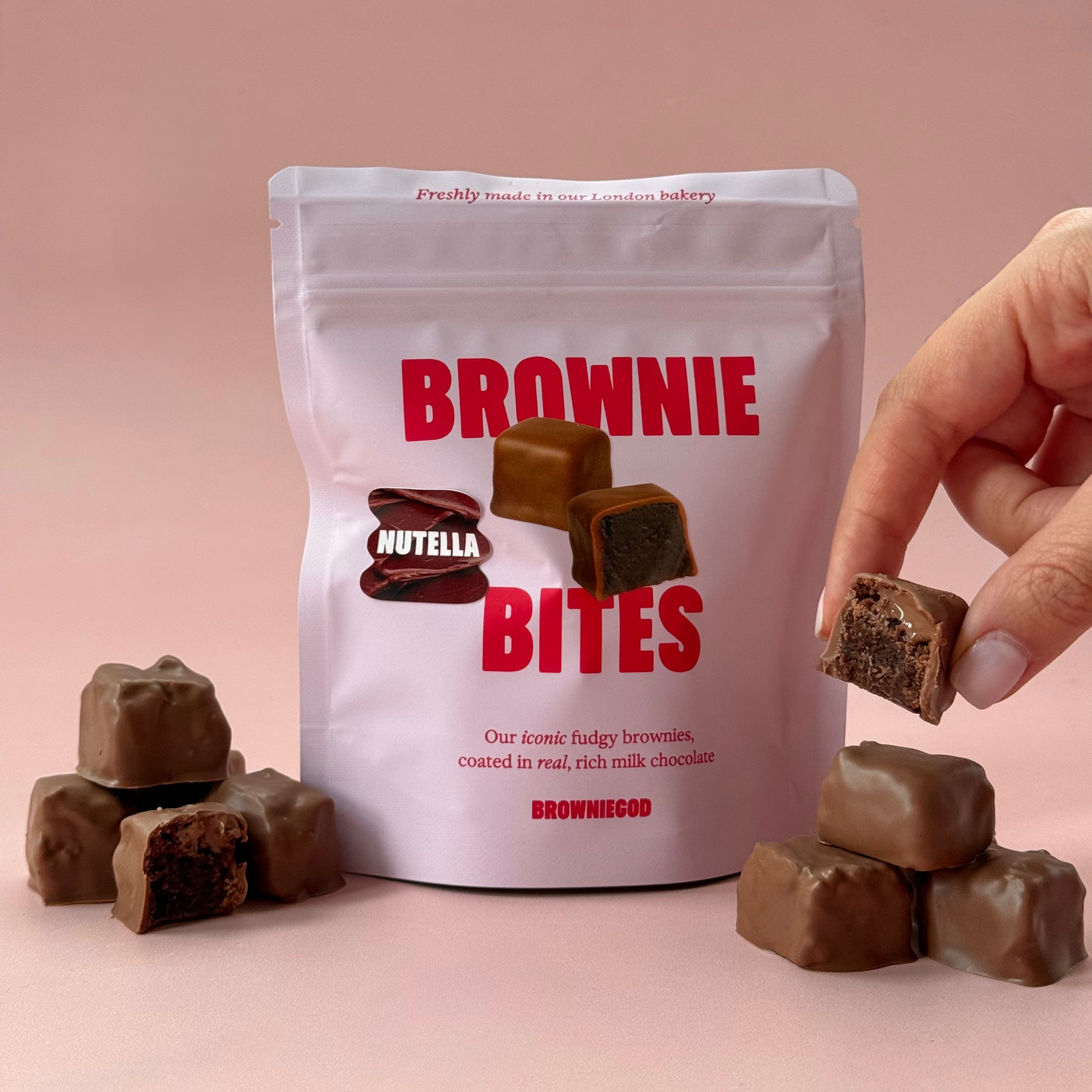 Nutella Brownie Bites pouch with milk chocolate brownie bites around it and a hand holding one