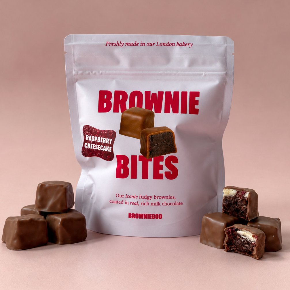 Raspberry cheesecake Brownie Bites pouch with milk chocolate brownie bites, one bitten to show the cheesecake filling
